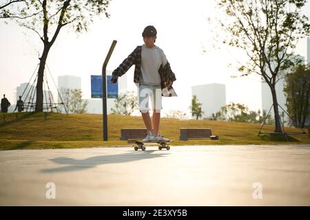 teenage asian boy skateboarding outdoors in the street Stock Photo