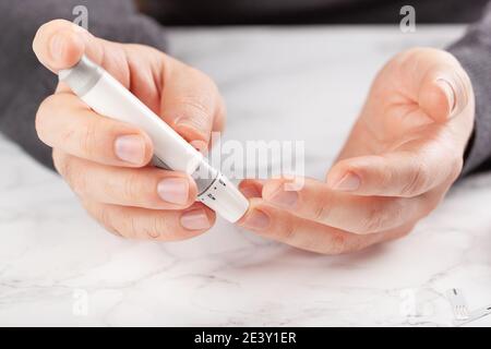 man hands using lancet on finger to check blood sugar or ketones level by glucose meter. medicine diabetes keto diet health care at home Stock Photo