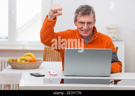 Happy mature man working with laptop from home Stock Photo