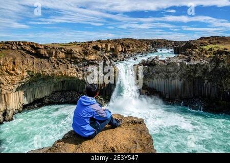 Traveler hiking in Icelandic summer landscape at the Aldeyjarfoss waterfall in north Iceland. The waterfall is situated in the northern part of the Stock Photo