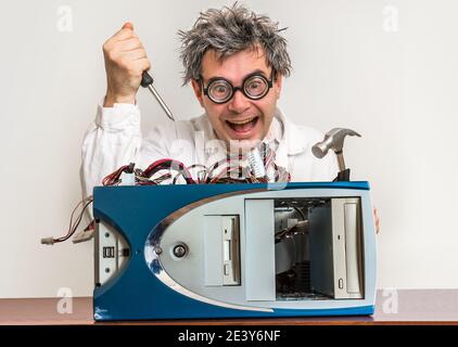 Crazy engineer or scientist repairing computer with hammer and screwdriver Stock Photo