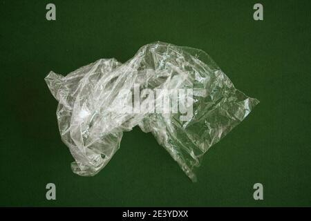 Crumpled plastic polyethylene bag on a green background. Contamination of the planet. Clear plastic bag. Zero waste concept. Stock Photo