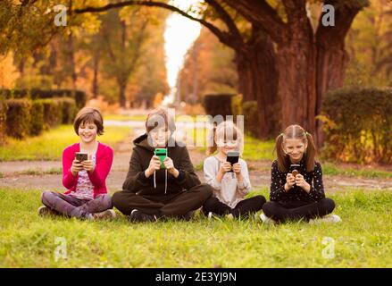 Group of friends girls using mobile phones and chatting together In park Stock Photo