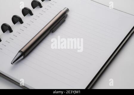 closeup of notebook with pen on white surface Stock Photo