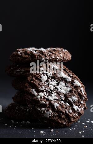 Closeup of a stack of chocolate cookies with white icing on a black background with copy space Stock Photo