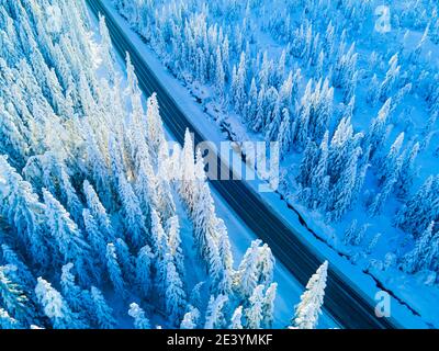 Highway through the winter forest. Aerial view on road and river on ...