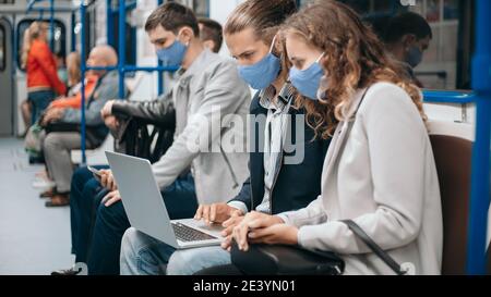 subway passengers wearing protective masks using their laptops. Stock Photo