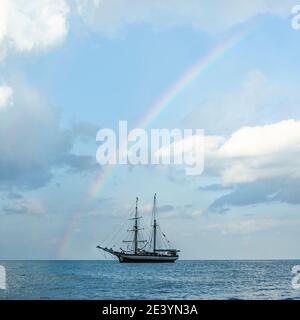 Sailship anchors under rainbow Stock Photo