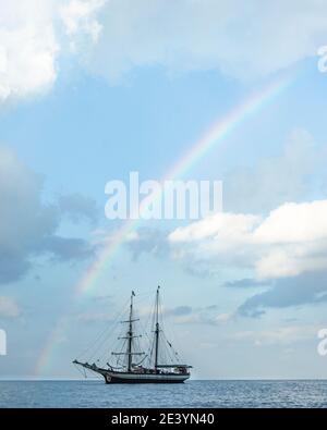 Sailship anchors under rainbow Stock Photo