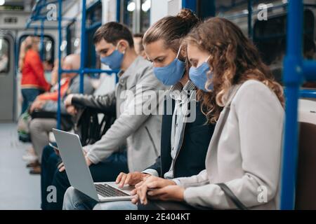 subway passengers wearing protective masks using their laptops. Stock Photo