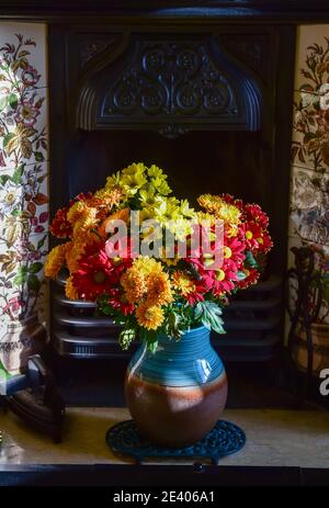 Chrysanthemums on display at home in a pottery vase placed in a fireplace