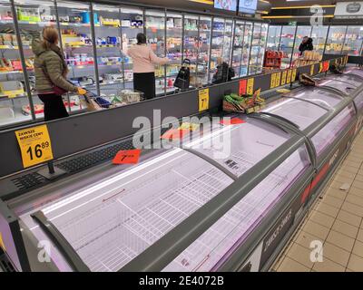 KATOWICE, POLAND - MARCH 14, 2020: People walk by empty meat refrigerators in a supermarket in Poland. Local people stockpiled food in anticipation of Stock Photo