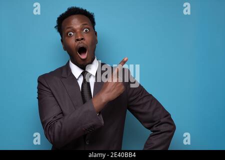 Wow, look here. Shocked african man opening mouth widely, pointing aside at copy space Stock Photo