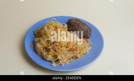Stewed white cabbage with a cutlet steak on a plate. A dish of Russian cuisine. Garnish in the USSR. Stock Photo