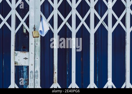 White paper notification attached to closed retractable folding metallic  gate.Metal collapsible sliding grille door normally use at shop houses in  Asi Stock Photo - Alamy