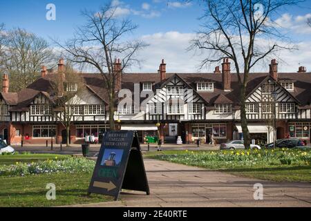 UK, England, West Midlands, Birmingham, Bournville, Daffodils on Bournville Village Green, wtih parade of shops in background Stock Photo