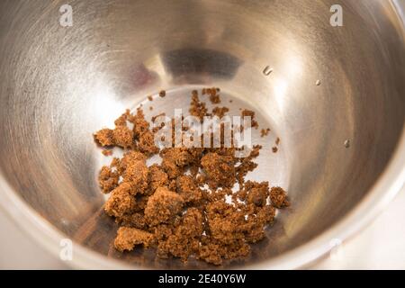 A pile of brown sugar in steel bowl. Close-up. Stock Photo