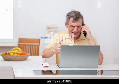 Annoyed mature man having problems while working from home with computer or internet - focus on the face Stock Photo