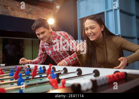 Young happy multiethnic couple having fun together, playing table soccer Stock Photo