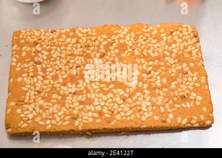 Ready carrot sponge cake with pine nuts. It is located on a metal surface. Close-up. Stock Photo