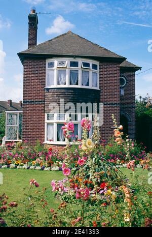 1920s/30s detached house of brick with front garden full of flowers evercreech somerset Stock Photo