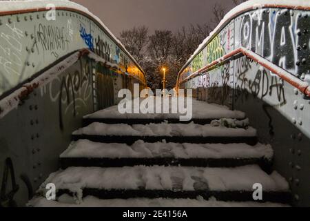 A bridge over a railway line covered in snow at night Stock Photo