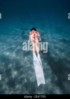 Freediver woman glide underwater with white fins. Summer freediving with attractive woman in ocean Stock Photo