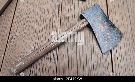 An old axe with a wooden handle on the top of the wooden table Stock Photo