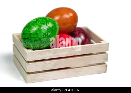 Colorful Easter eggs in a wooden box against a white background Stock Photo
