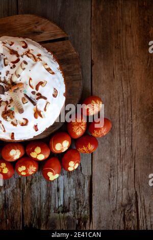 Easter cake and colored eggs. Rustic food on a wooden table. Traditional egg colored with onion peel. Clover and dill leaves pattern. Classic food for Stock Photo