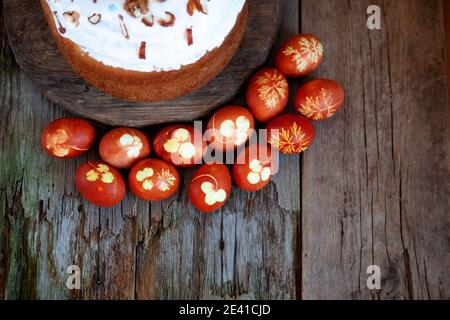 Easter cake and colored eggs. Rustic food on a wooden table. Traditional egg colored with onion peel. Clover and dill leaves pattern. Classic food for Stock Photo