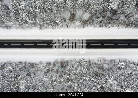 country road going through the beautiful snow covered landscapes, aerial view, drone photography Stock Photo