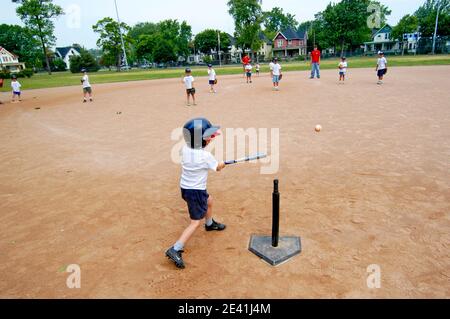 5 to 7 year old boys and girls taken baseball lessons by being introduced to T Ball baseball little league Stock Photo