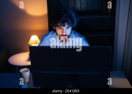 Close-up face of focused bearded man looking intently at monitor screen while working on computer. Stock Photo