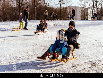 POZNAN, POLAND - Jan 17, 2021: Man and boy sitting on a wooden slide at a park on a cold winter day Stock Photo