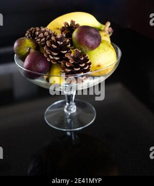 Still Life in natural light. Footed glass fruit dish with fresh fruit display, reflected on marble top. Food photography Stock Photo