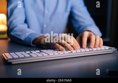 Close-up view of hands of unrecognizable man working typing on wireless keyboard computer, Stock Photo