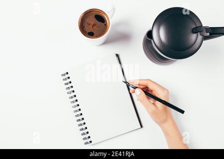 Home office workplace with female hand writing in blank paper notebook Stock Photo