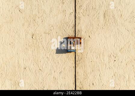 Rusty clasp with padlock locking wooden doors. Minimal. Rough wood surface Stock Photo