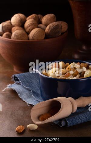 Whole and peeled walnuts in ceramic and wooden dishes on a dark background Stock Photo