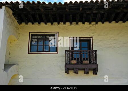 Old Colonial house facade with traditional wooden windows, rooftop and balcony on a white washed stucco wall in Zacatlán de las Manzanas, Mexico. Stock Photo