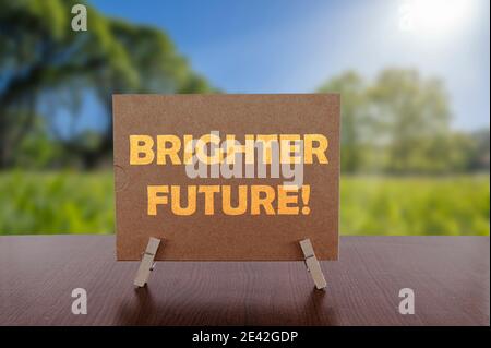 Brighter future text on card on the table with sunny green park background. Stock Photo