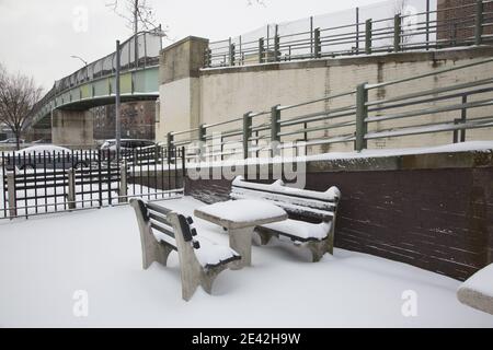 Snow covered table and benches in a pocket park nestled next to a pedestrian bridge in the Windsor Terrace neighborhood of Brooklyn, New York. Stock Photo