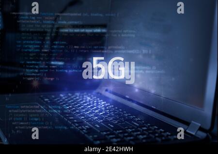 5G inscription against laptop and code background. Technology concept. Stock Photo