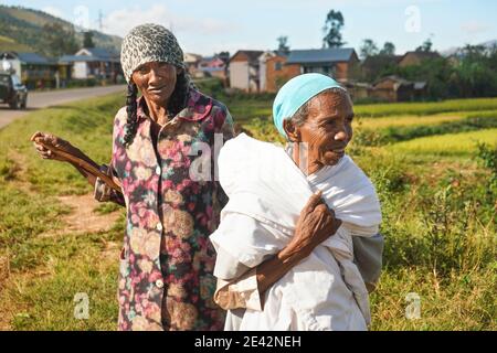 Manandoana, Madagascar - April 26, 2019: Unknown senior Malagasy women standing next to rice field where they worked on sunny day. People in this part Stock Photo