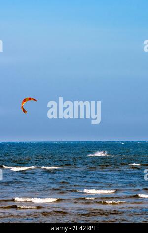 A young man is engaged in extreme kiteboarding in the Gulf of Riga on October 21, 2019 at Cape Kolka in Latvia. Stock Photo