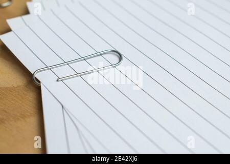 Metal paper clips and colorful  push pins with some sheets on a wooden table Stock Photo