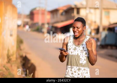 young black man using his phone rejoices Stock Photo