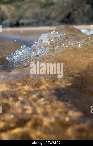 Waves breaking on the coast, spray, white water and light reflected on the surface of the water Stock Photo