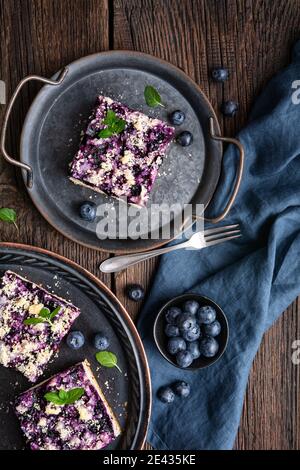 Delicious juicy dessert, blueberry pie slices topped with a sweet crunchy streusel, decorated with fresh berries on rustic wooden background Stock Photo